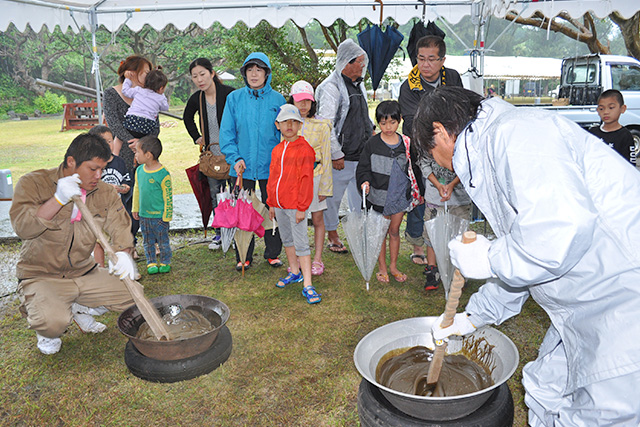 黒砂糖作りを身近で見学する親子連れ