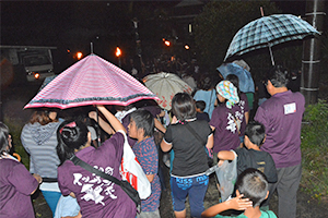 雨の中松明に続く参加者