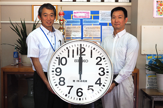 掛け時計を持つ森潤一郎さん（右）と狩集校長（左）