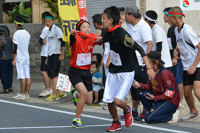 第2中継所でタスキをつなぐ亀徳の福沢天希選手と田畑恭介選手（手前）