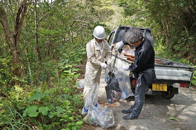 林道周辺に不法投棄されたゴミを回収する参加者