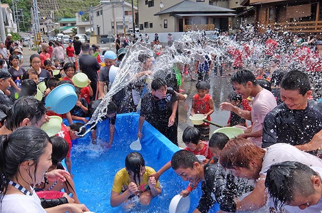 笑顔で水を掛けあう住民ら